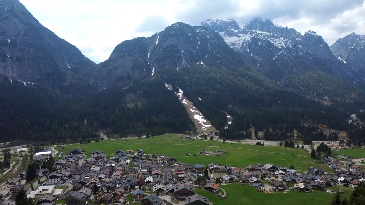Borgata Bach und der Talkessel von Sappada von der Drohne: die Häuser, die Wiesen im Talboden, die Piste und die Berge im Süden