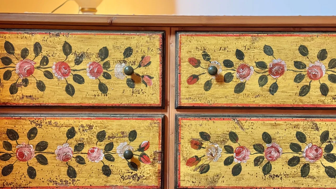 Detail der mit Rosen auf gelbem Grund bemalten Schubladen