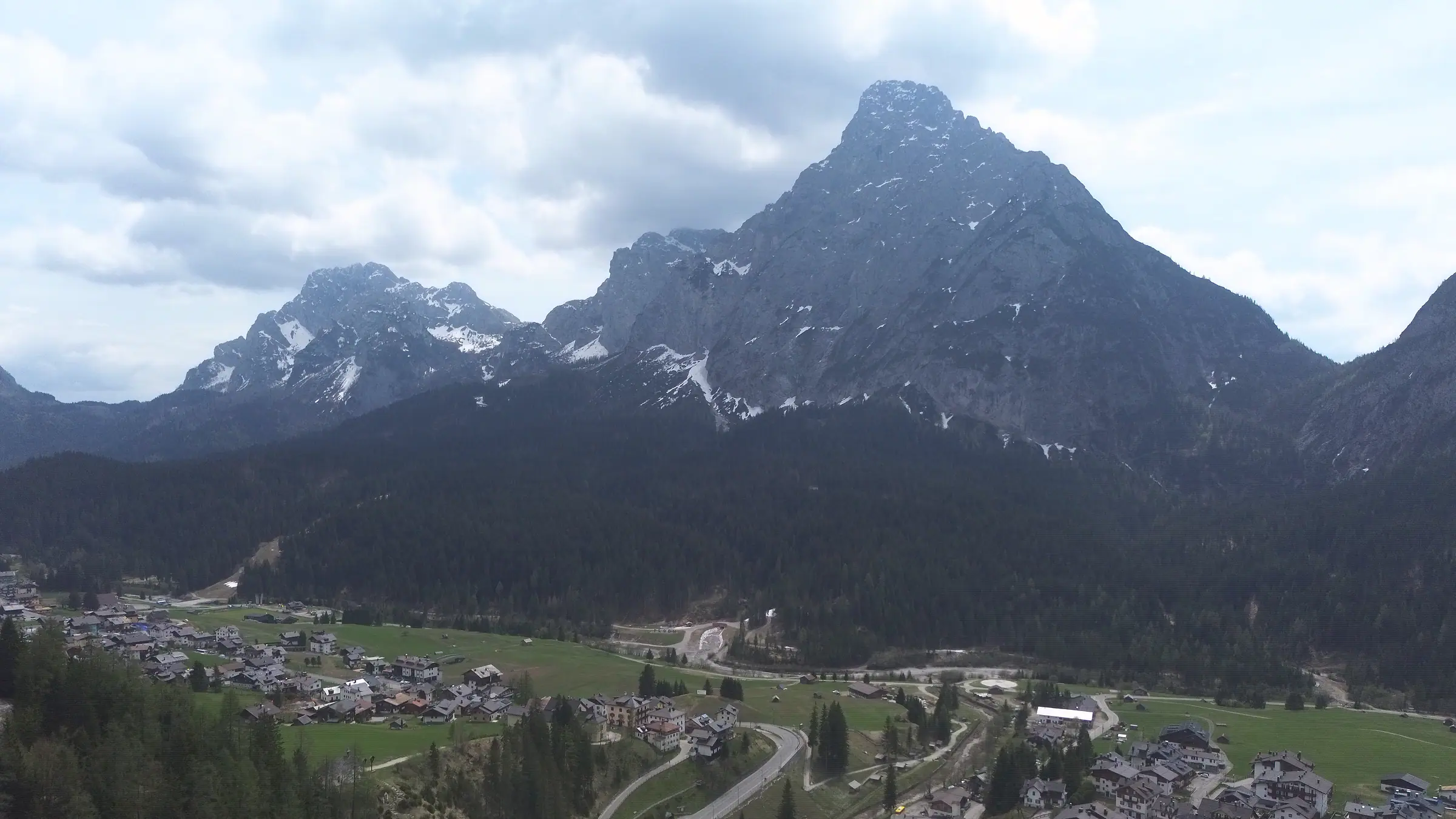 Monte Siera, piramida iz svetle skale nad gozdom; ob vznožju serpentine ceste, soteska potoka ter hiše zaselkov Bach in Mühlbach.