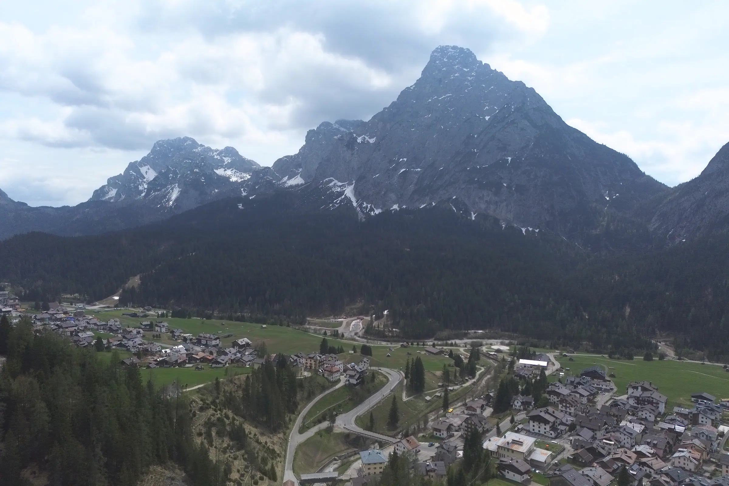 Der Monte Siera, eine Pyramide aus hellem Fels über dem Wald; zu seinen Füßen die Kehren der Straße, die Bachschlucht und die Häuser von Bach und Mühlbach.