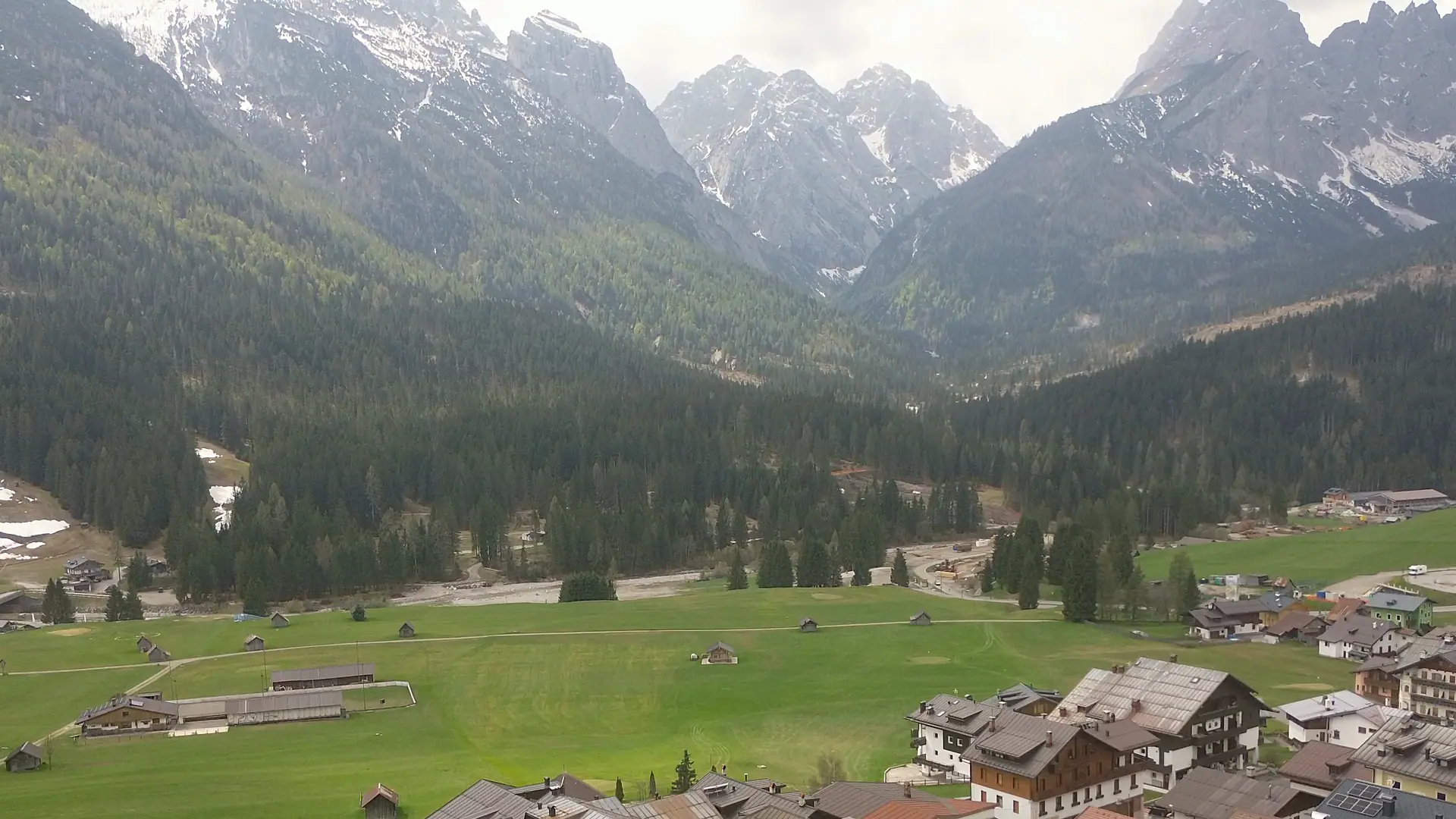 Drone footage of the mountains south and west of Sappada: the forest with the ski run, the still snow-covered peaks beyond the saddle and, turning west, the rock ridges of the Terze under the clouds.